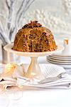 Steamed ginger and date pudding drizzled with toffee sauce and decorated with star anise on a cake stand