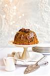 Steamed ginger and date pudding drizzled with toffee sauce and decorated with star anise on a cake stand