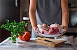 A woman holding a bowl of different meat varieties (ingredients for Cocido madrileno - a Spanish stew)