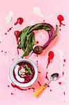 Beet soup in a white bowl on colored construction paper surface - healthy food