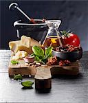 An arrangement of tomatoes, olive oil, parmesan, garlic, pine nuts and basil on a chopping board