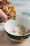 Granola being poured into a bowl of milk