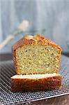 A lemon and poppyseed loaf cake on a wire cooling rack (with one slice cut off)