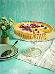 Lemon tart topped with berries with a slice taken out