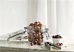 Hazelnuts in and next to a glass jar and a nutcracker on a rustic kitchen table