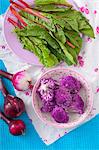 An arrangement of beetroot leaves, red onion and purple cauliflower