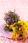 An arrangement of blossoming thyme and yellow courgette with flowers on a plate