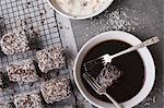 Making Lamingtons - dipping in chocolate icing