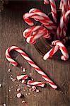 Christmas candy canes in a gold traditional mug and one cane on a rustic wooden surface