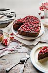 Chocolate cake in a shape of a heart with chocolate glaze and pomegranate seeds