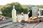 Bottled gin punch with pineapple garnish in silver rimmed glasses outdoor