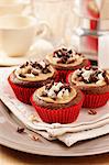 Mocha chestnut cupcakes on a cream napkin and plate with coffee cups and percolator in background