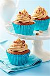 Sticky toffee cupcakes with caramel icing and fudge pieces in blue metalic cupcake cases