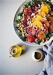 Three types of orange slices, blood, cara cara and navel oranges on top of a bed of chickpea arugula salad