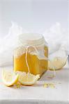 Lemon Curd in a glass jar with sliced lemons