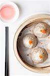 Steamed Chinese dumplings with fish roe in bamboo steaming basket with chopsticks and dipping sauce