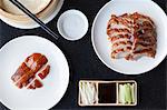 Slices of crispy Peking duck and duck skin with pancakes spring onions cucumber and hoisin sauce