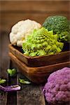 Fresh organic white and purple cauliflower, broccoli, romanesco in wooden bowl