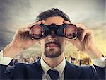 Businessman looks at the city from the roof with binoculars