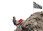 Businessman climb a mountain with a small car to get to the flag. Achievement business goal and Difficult career concept
