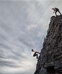 Businessman helps another man to climb a mountain. Businessmen collaborate to achieve a goal concept.