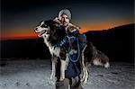 Portrait of mature man carrying dog in snow at night