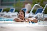 Mature woman leaning on swimming pool side, Dubai, United Arab Emirates