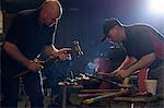 Farriers forging horseshoe on anvil