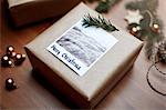 Gift wrapped in brown paper and decorated with fern and note reading Merry Christmas