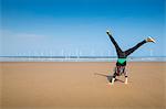 Mature woman doing cartwheel on Redcar beach, North Yorkshire, UK