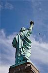 Low angle view of Statue of Liberty and airplane in blue sky, New York city, USA