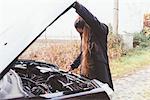 Woman looking at car engine on roadside