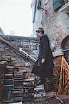 Young woman moving up stacked book stairway, Venice, Italy