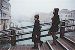 Couple moving down stairway over misty canal, Venice, Italy