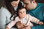 Baby girl looking up while being snuggled by her parents