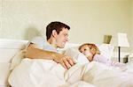 Female toddler and father gazing at each other in bed