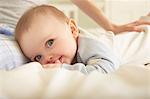 Portrait of baby girl lying on bed with mother