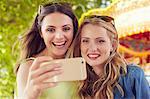 Women taking selfie, carousel in background, London, UK