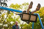 Father pushing daughter on playground swing