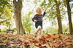 Girl playing in autumn leaves