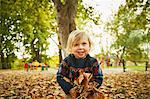 Girl playing in autumn leaves