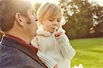 Father carrying daughter holding dandelion clock