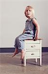 Girl sitting on old cabinet looking away