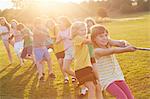 Team of girls and boys pulling for tug o'war on playing field