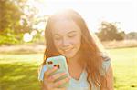 Girl looking at smartphone in sunlit park