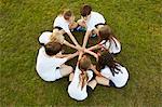 Overhead view of boy and girl sport team sitting on grass in circle on playing field