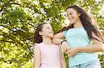 Girl and big sister looking at each other in park