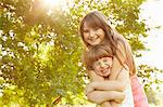 Portrait of girl being hugged by big sister in park