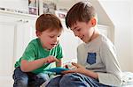 Male toddler and brother looking at digital tablet