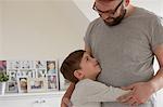 Boy hugging father in living room